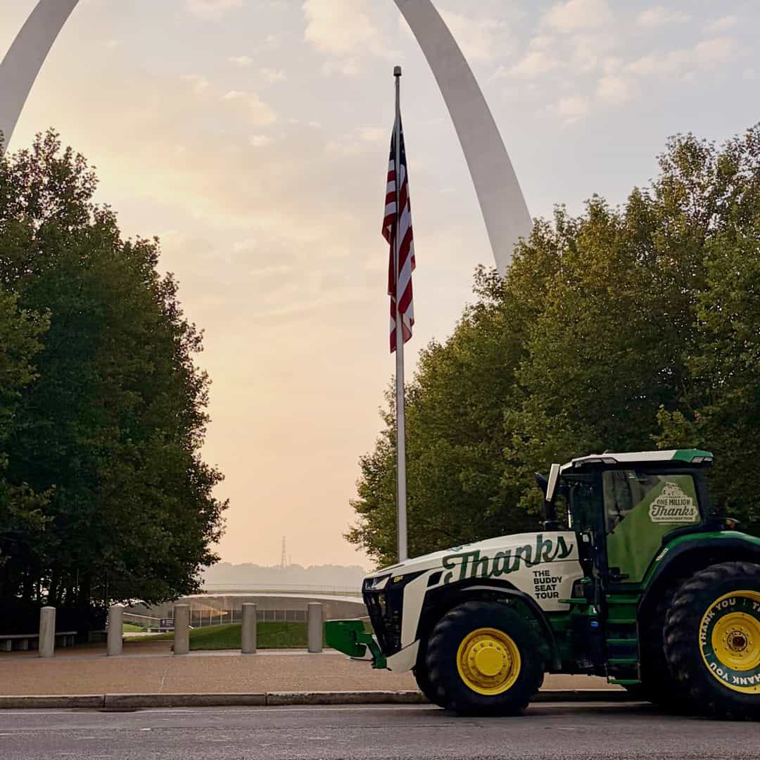 The Buddy Seat Tour tractor in front of an American flag and the St. Louis arch